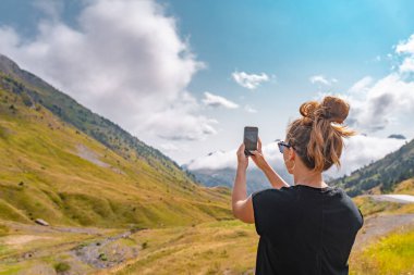 Genç yürüyüşçü kadın bir dağın tepesinde cep telefonuyla fotoğraf çekiyor. Keşif Yolculuğu Konsepti. Yüksek kalite fotoğraf