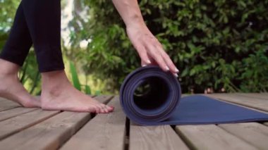 Kadın, yoga piposunun üzerinde parmaklarıyla hasırı yuvarlıyor. Bulanık arka plan yavaş çekim kamerası seyahat ediyor. Yüksek kaliteli FullHD görüntüler