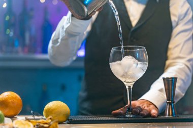 Barmen, gece kulübünde kokteyl hazırlıyor. Malzeme ekliyor ve bar tezgahında uzman içkiler yapıyor. Yüksek kalite fotoğraf