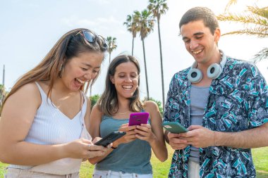 Çok kültürlü genç arkadaşlar akıllı telefonlar ve sosyal medya kullanarak eğleniyorlar. Mobil oyunlar.