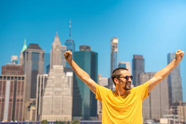 Young attractive man with raised arms happy smiling win celebration in the city skyline. High quality photo