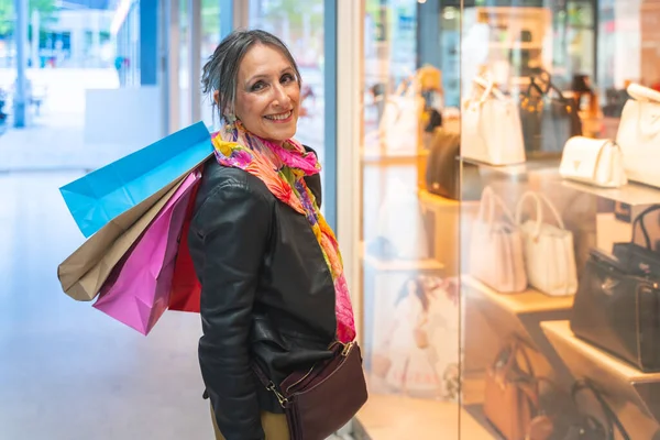 Attractive lady with shopping bags happy smiling looking to camera in front of a store. Holiday shopping sales. High quality photo