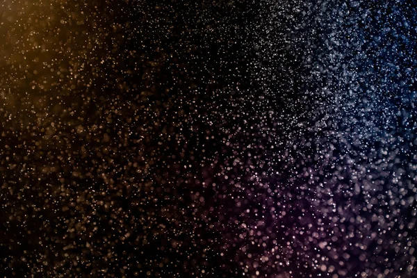 Dust particles floating on a colorful rainbow light on black background. Glittering sparkling flickering overlay. High quality photo