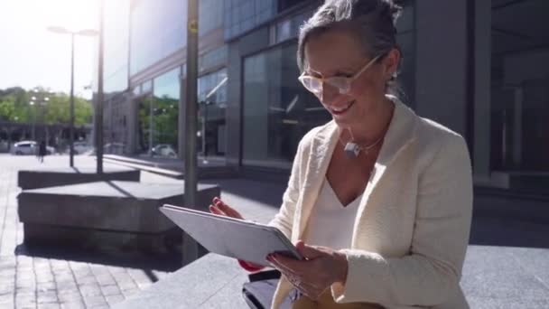 現代都市で笑顔のタブレットで働くシニアビジネス女性 テクノロジーの概念 高品質のフルHd映像 — ストック動画