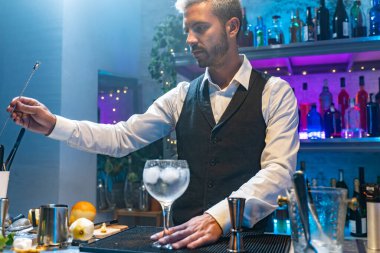 Beyaz gömlekli ve siyah önlüklü bir barmen gece kulübünde kokteyl hazırlıyor. Yakın hayat. Yüksek kalite fotoğraf