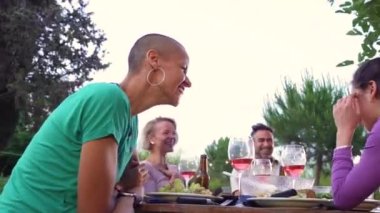 Mutlu arkadaşlar büyük bir gülümsemeyle gülüyor ve bir yaz lokantasında kadeh kaldırıyorlar. Ev verandasında yemek yerken gülümseyen insanlar. Gülümseme, neşe konsepti. Yüksek kalite 4k görüntü