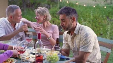 Bir grup arkadaş yaz tatilinde avluda gülerek yiyip içiyorlar. Yüksek kalite fotoğraf