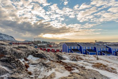 Arktik Eskimolar gün batımı manzarasında kayalık tepelerde oturuyorlar. Nuuk, Grönland