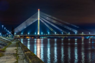 Daugava nehrinin kıyısındaki Vansu kablo köprüsüne gece görüşü sokak ışıklarıyla renklendirilmiş, Riga, Letonya