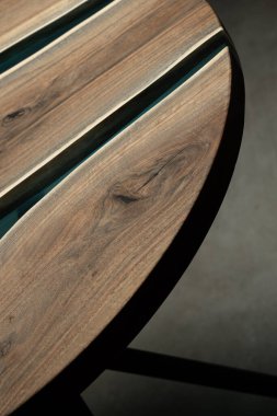 Pahalı eski mobilyalar. Masa epoksi reçineyle kaplanmış ve verniklenmiş. Lüks kaliteli ahşap işleme. Koyu arkaplanda tahta bir masa. Yuvarlak bir ağaç tablasında mavi bir epoksi nehri.