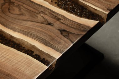 Pahalı eski mobilyalar. Masa epoksi reçineyle kaplanmış ve verniklenmiş. Lüks kaliteli ahşap işleme. Kahve çekirdekli bir tahta parçasında şeffaf bir epoksi nehri..