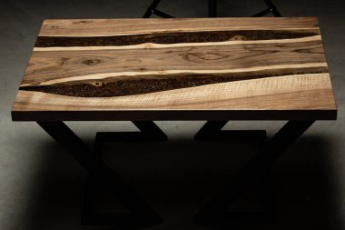 Pahalı eski mobilyalar. Masa epoksi reçineyle kaplanmış ve verniklenmiş. Lüks kaliteli ahşap işleme. Kahve çekirdekli bir tahta parçasında şeffaf bir epoksi nehri..