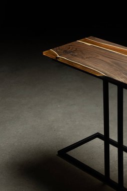 Pahalı eski mobilyalar. Masa epoksi reçineyle kaplanmış ve verniklenmiş. Lüks kaliteli ahşap işleme. Koyu arkaplanda tahta bir masa. Dikdörtgen bir ağaç tablasında altın bir epoksi nehri..