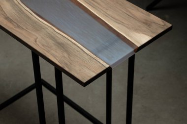 Pahalı eski mobilyalar. Masa epoksi reçineyle kaplanmış ve verniklenmiş. Lüks kaliteli ahşap işleme. Beton zeminde tahta bir masa. Dikdörtgen bir ağaç tabakasında mor bir epoksi nehri.