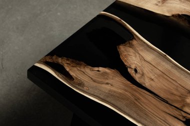 Pahalı eski mobilyalar. Masa epoksi reçineyle kaplanmış ve verniklenmiş. Lüks kaliteli ahşap işleme. Beton zeminde tahta bir masa. Dikdörtgen bir ağaç tabakasında siyah bir epoksi nehri..