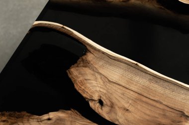 Pahalı eski mobilyalar. Masa epoksi reçineyle kaplanmış ve verniklenmiş. Lüks kaliteli ahşap işleme. Beton zeminde tahta bir masa. Dikdörtgen bir ağaç tabakasında siyah bir epoksi nehri..