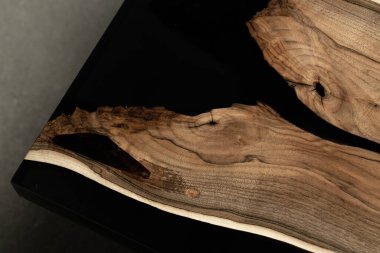 Pahalı eski mobilyalar. Masa epoksi reçineyle kaplanmış ve verniklenmiş. Lüks kaliteli ahşap işleme. Beton zeminde tahta bir masa. Dikdörtgen bir ağaç tabakasında siyah bir epoksi nehri..