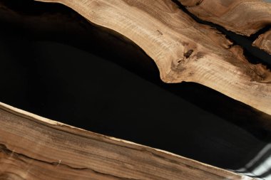 Pahalı eski mobilyalar. Masa epoksi reçineyle kaplanmış ve verniklenmiş. Lüks kaliteli ahşap işleme. Beton zeminde tahta bir masa. Dikdörtgen bir ağaç tabakasında siyah bir epoksi nehri..