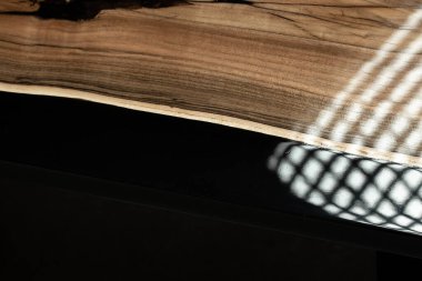 Pahalı eski mobilyalar. Masa epoksi reçineyle kaplanmış ve verniklenmiş. Lüks kaliteli ahşap işleme. Beton zeminde tahta bir masa. Dikdörtgen bir ağaç tabakasında siyah bir epoksi nehri..