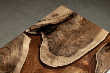 Pahalı eski mobilyalar. Masa epoksi reçineyle kaplanmış ve verniklenmiş. Lüks kaliteli ahşap işleme. Koyu arkaplanda tahta bir masa. Dikdörtgen bir ağaç tablasında altın bir epoksi nehri..