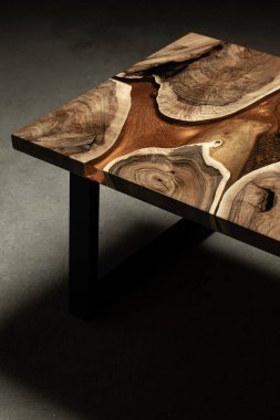 Pahalı eski mobilyalar. Masa epoksi reçineyle kaplanmış ve verniklenmiş. Lüks kaliteli ahşap işleme. Koyu arkaplanda tahta bir masa. Dikdörtgen bir ağaç tablasında altın bir epoksi nehri..