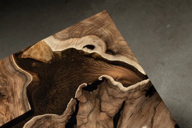 Pahalı eski mobilyalar. Masa epoksi reçineyle kaplanmış ve verniklenmiş. Lüks kaliteli ahşap işleme. Koyu arkaplanda tahta bir masa. Dikdörtgen bir ağaç tablasında altın bir epoksi nehri..