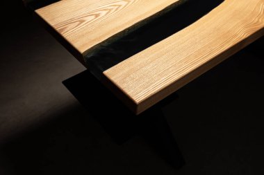 Pahalı eski mobilyalar. Masa epoksi reçineyle kaplanmış ve verniklenmiş. Lüks kaliteli ahşap işleme. Koyu arkaplanda tahta bir masa. Epoksi reçineden yapılmış siyah nehir..