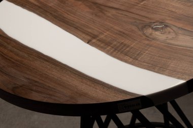 Pahalı eski mobilyalar. Masa epoksi reçineyle kaplanmış ve verniklenmiş. Lüks kaliteli ahşap işleme. Koyu arkaplanda tahta bir masa. Yuvarlak bir ağaç tablasında beyaz bir epoksi nehri.