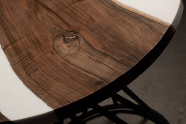 Pahalı eski mobilyalar. Masa epoksi reçineyle kaplanmış ve verniklenmiş. Lüks kaliteli ahşap işleme. Koyu arkaplanda tahta bir masa. Yuvarlak bir ağaç tablasında beyaz bir epoksi nehri.