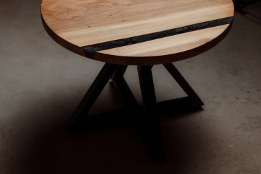 Pahalı eski mobilyalar. Masa epoksi reçineyle kaplanmış ve verniklenmiş. Lüks kaliteli ahşap işleme. Koyu arkaplanda tahta bir masa. Yuvarlak bir ağaç tablasında siyah bir epoksi nehri.