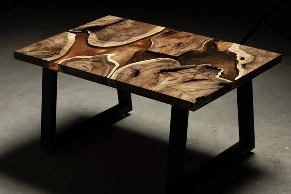 Pahalı eski mobilyalar. Masa epoksi reçineyle kaplanmış ve verniklenmiş. Lüks kaliteli ahşap işleme. Koyu arkaplanda tahta bir masa. Dikdörtgen bir ağaç tablasında altın bir epoksi nehri..