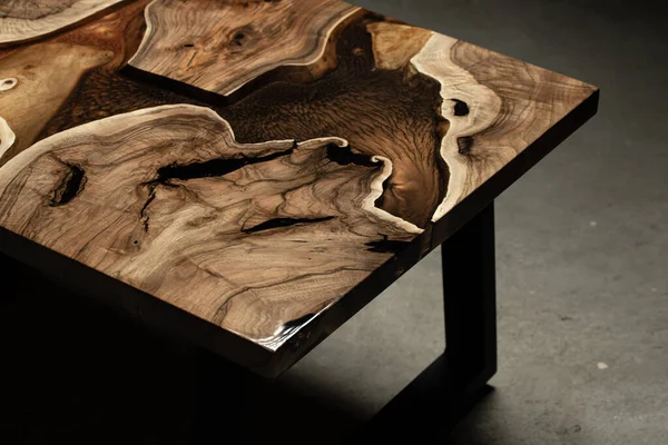 Pahalı eski mobilyalar. Masa epoksi reçineyle kaplanmış ve verniklenmiş. Lüks kaliteli ahşap işleme. Koyu arkaplanda tahta bir masa. Dikdörtgen bir ağaç tablasında altın bir epoksi nehri..