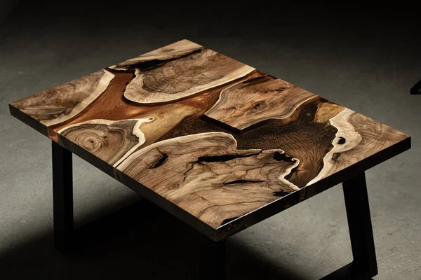 Pahalı eski mobilyalar. Masa epoksi reçineyle kaplanmış ve verniklenmiş. Lüks kaliteli ahşap işleme. Koyu arkaplanda tahta bir masa. Dikdörtgen bir ağaç tablasında altın bir epoksi nehri..