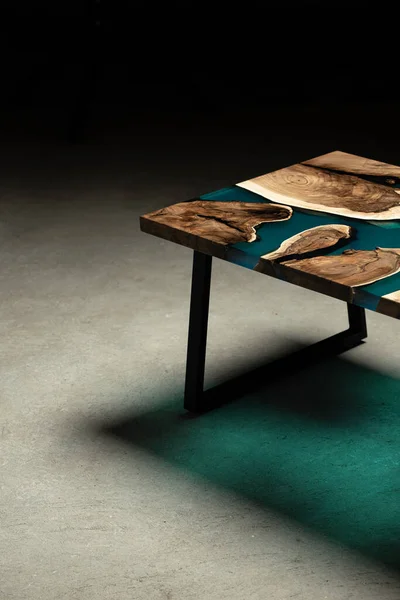 Pahalı eski mobilyalar. Masa epoksi reçineyle kaplanmış ve verniklenmiş. Lüks kaliteli ahşap işleme. Beton zeminde tahta bir masa. Dikdörtgen bir levhada bir deniz tutkalı nehri..