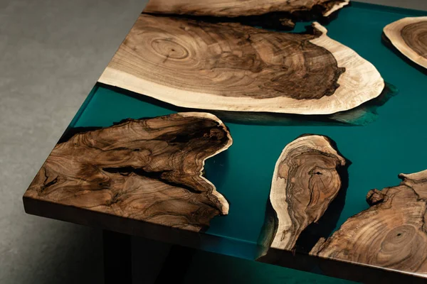 Pahalı eski mobilyalar. Masa epoksi reçineyle kaplanmış ve verniklenmiş. Lüks kaliteli ahşap işleme. Beton zeminde tahta bir masa. Dikdörtgen bir levhada bir deniz tutkalı nehri..