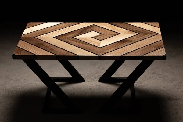 Expensive vintage furniture. The table is covered with epoxy resin and varnished. Luxury quality wood processing. Wooden table on a dark background. Swirling geometric patterns in the form of a maze.
