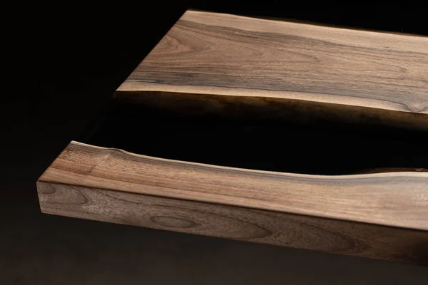 Pahalı eski mobilyalar. Masa epoksi reçineyle kaplanmış ve verniklenmiş. Lüks kaliteli ahşap işleme. Koyu arkaplanda tahta bir masa. Yuvarlak bir ağaç tablasında siyah bir epoksi nehri.