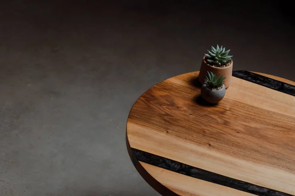 Expensive vintage furniture. The table is covered with epoxy resin and varnished. Luxury quality wood processing. Home tabletop cacti in concrete pots and geometric figure.