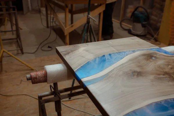 Özel ahşap masa imalatı. Epoksi reçine elementli tezgah yapımı için atölye çalışması. Zımparaladıktan sonra bir marangozhanede tozlu bir masa üstü..