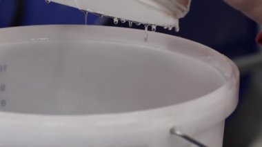 Epoksi reçine bileşenlerini boyayla karıştırıyorum. Özel mobilya imalatının aşamalarından biri. Lüks kaliteli ahşap işleme. Sıvıyı bir konteynırdan diğerine aktarmak.