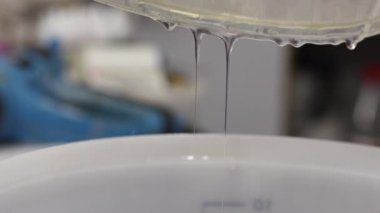 Epoksi reçine bileşenlerini boyayla karıştırıyorum. Özel mobilya imalatının aşamalarından biri. Lüks kaliteli ahşap işleme. Sıvıyı bir konteynırdan diğerine aktarmak.