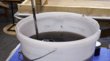 Epoksi reçine bileşenlerini boyayla karıştırıyorum. Özel mobilya imalatının aşamalarından biri. Lüks kaliteli ahşap işleme. 