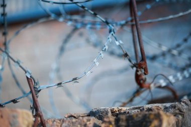 Eski duvarın arka planında dikenli teller var.