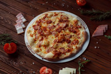 Tahta bir masada etli ve sebzeli pizza. 