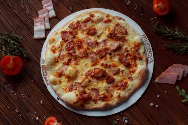 Tahta bir masada etli ve sebzeli pizza. 