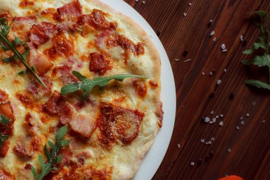 Tahta bir masada etli ve sebzeli pizza. 