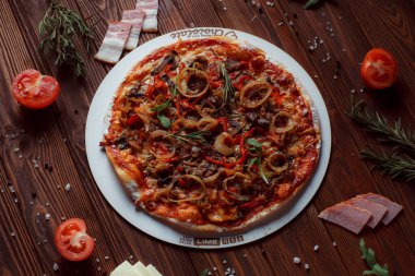 Tahta bir masada etli ve sebzeli pizza. 