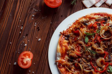 Tahta bir masada etli ve sebzeli pizza. 