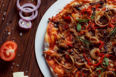 Tahta bir masada etli ve sebzeli pizza. 