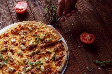 Tahta bir masada etli ve sebzeli pizza. 